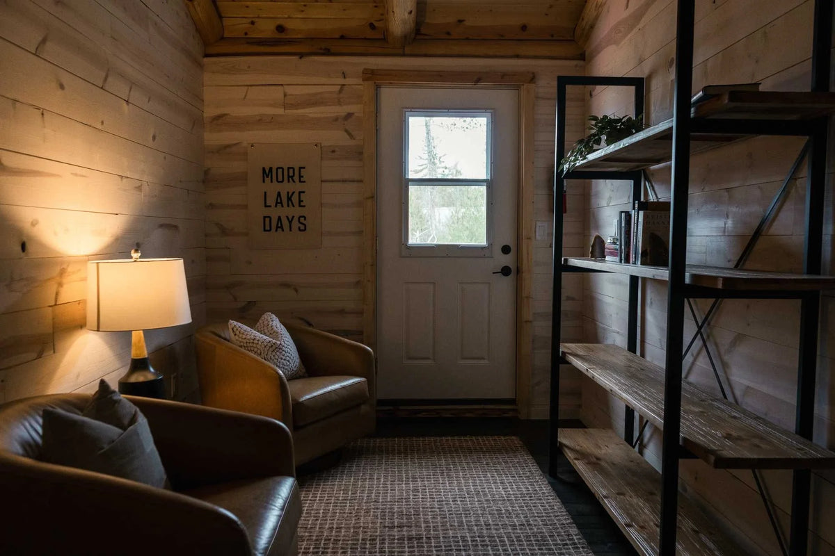 A cozy cabin with Duluth Pack with leather chairs, a book shelf, and a balcony.