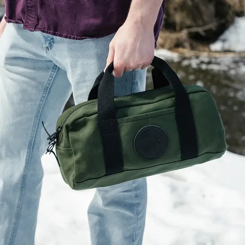 NEW Limited Edition Lake Erie Utility Bag Being Held By A Man On The Snow In Front Of A River