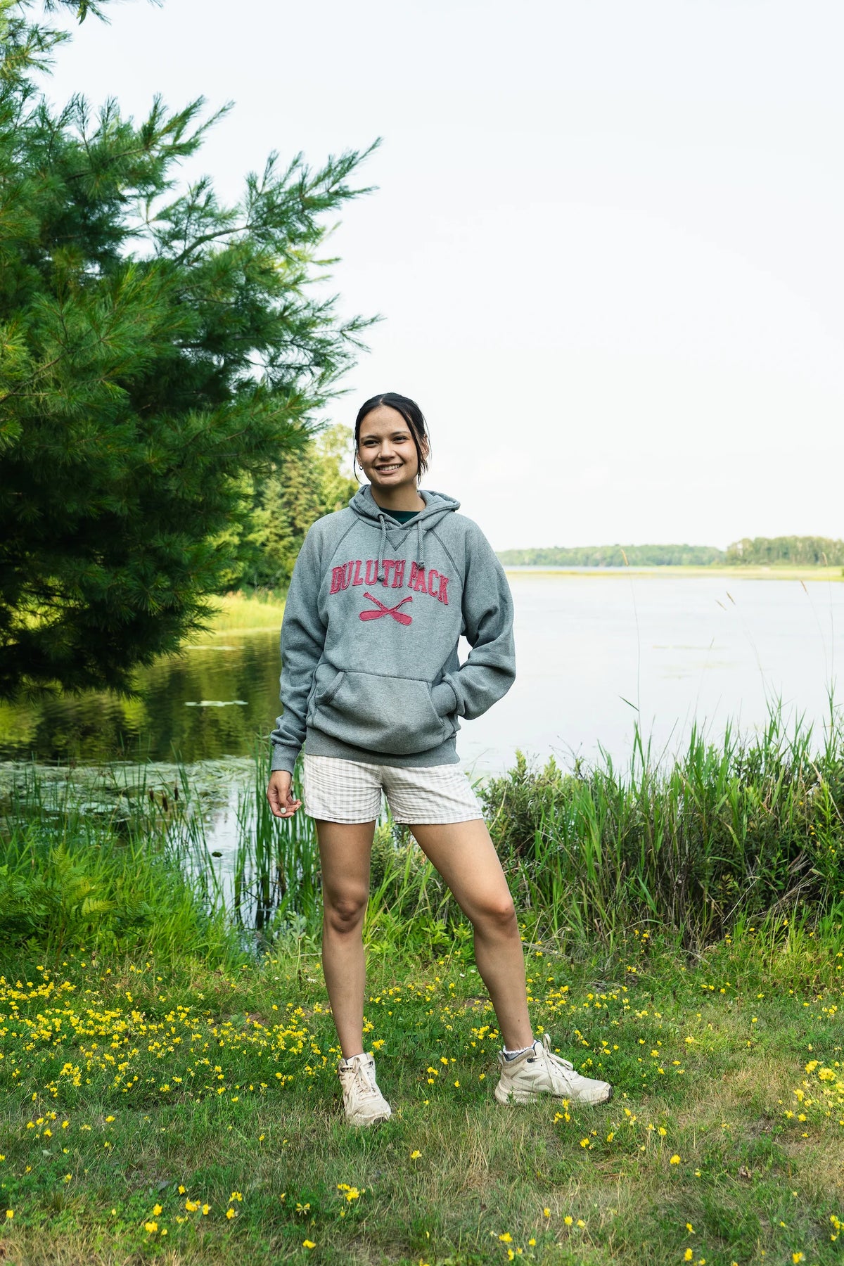 A woman wearing a Duluth Pack sweatshirt with a marshy lake in the background