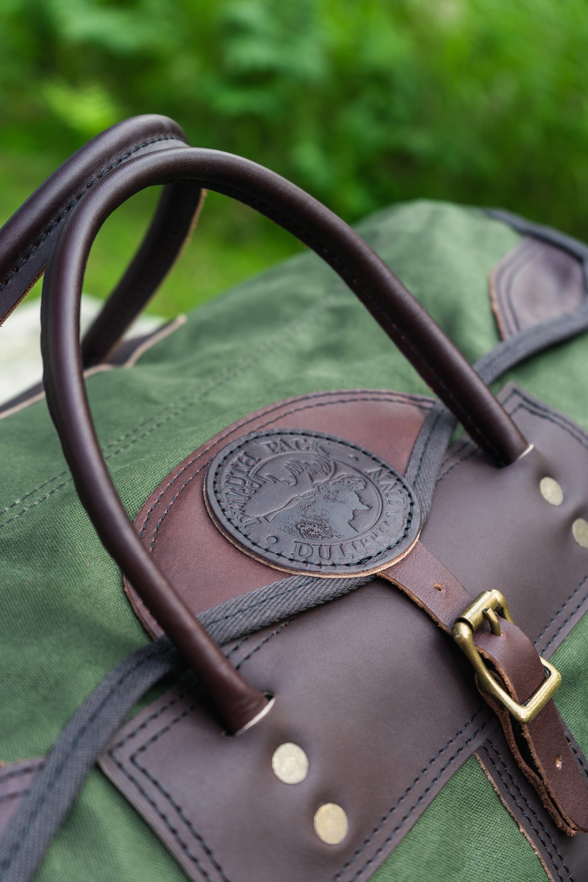 Duluth Pack New Sportsman Duffel in Olive Drab with a forest in the background.