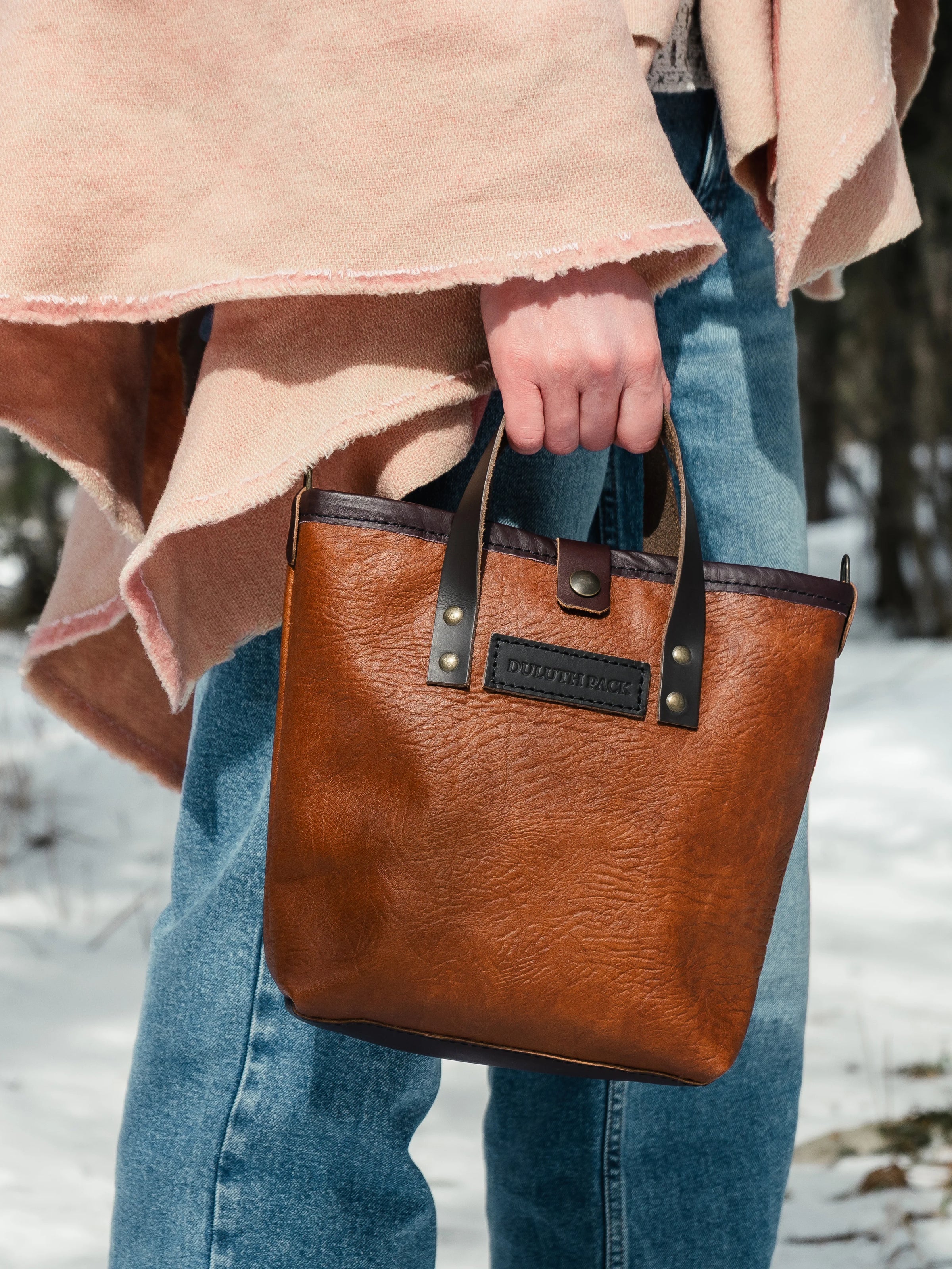 woman holding a duluth pack honeyberry tote wearing a shawl with a snowy background
