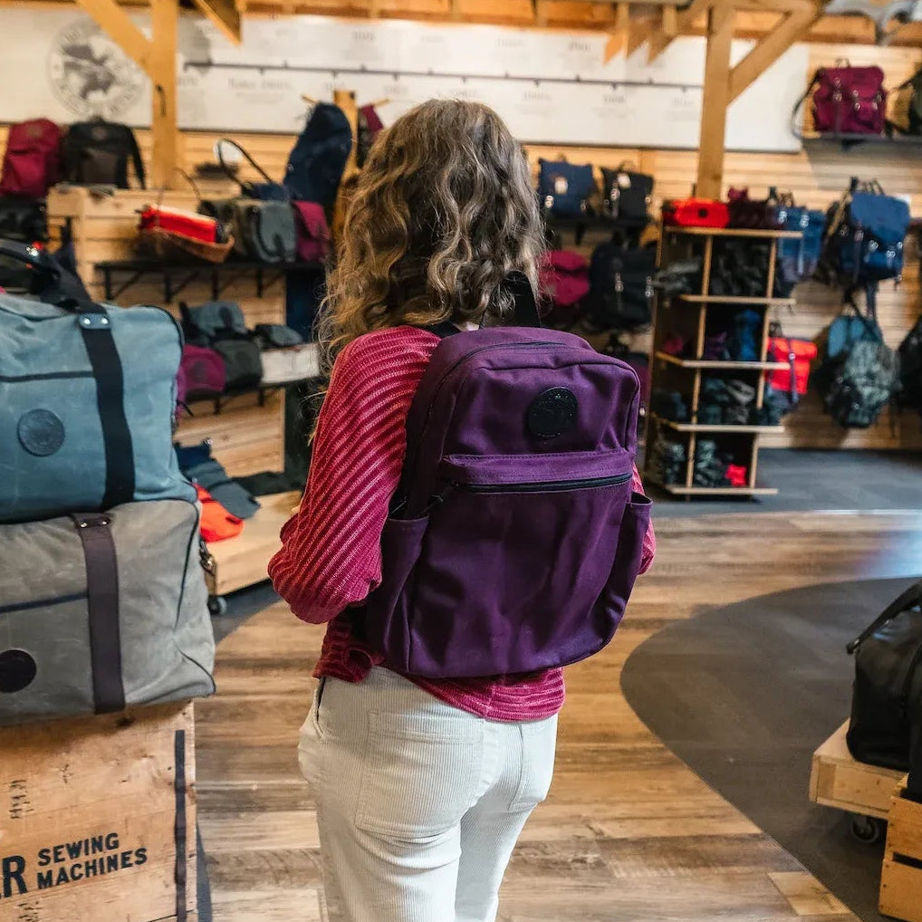 A woman wearing a Duluth Pack Limited Edition Waxed Grape Standard Backpack