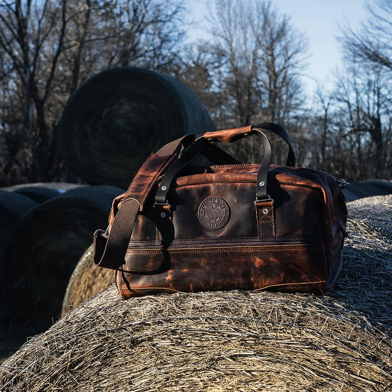 Duluth Pack Heritage Leather Weekender Duffel on a hay bale with hay bales in the background