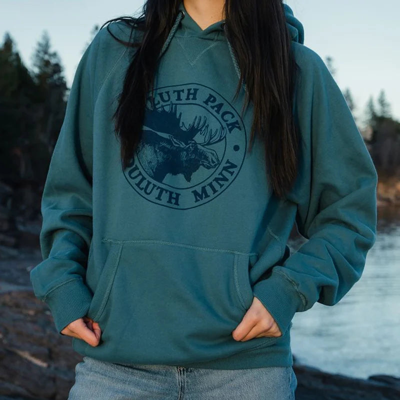 Duluth Pack Logo Sweatshirt in muted teal with iconic moose logo, warm and cozy for outdoor wear, photographed by water with forest background, from LAKESHIRTS, INC.
