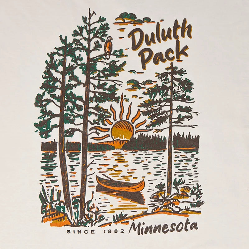 Duluth Pack Canoe Adventure T-Shirt in cappuccino color featuring a Northwoods canoe scene with trees, sunset, and wildlife, designed for outdoor enthusiasts by LAKESHIRTS, INC.