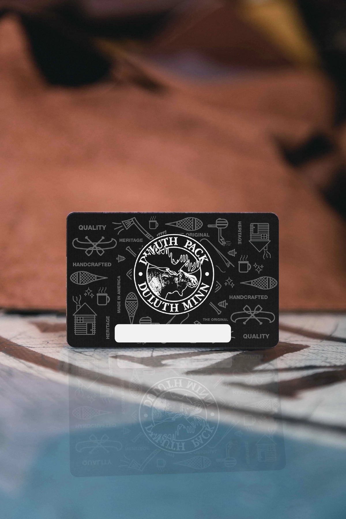 Duluth Pack E-Gift Card with full grain leather in the background