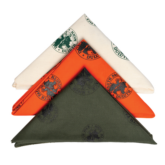 Natural, orange and olive drab bandanas folded neatly and stacked on each other on a white background