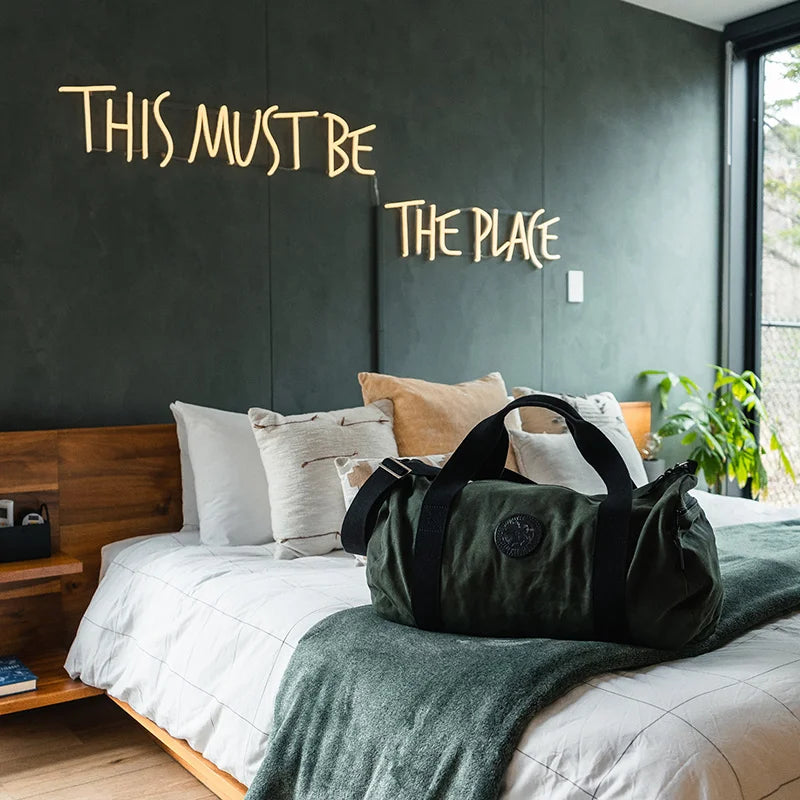 Round Duffel on Bed with Sign This Must Be The Place